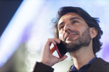 Gece vakti arka planda şehir manzarası olan akıllı telefon kullanan genç bir adamın görüntüsü. Yüksek kalite fotoğraf. Gece vakti arka planda şehir manzarası olan akıllı telefon kullanan genç bir adamın görüntüsü. Yüksek kalite fotoğraf. 