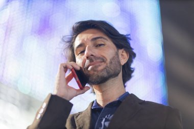 Gece vakti arka planda şehir manzarası olan akıllı telefon kullanan genç bir adamın görüntüsü. Yüksek kalite fotoğraf. Gece vakti arka planda şehir manzarası olan akıllı telefon kullanan genç bir adamın görüntüsü. Yüksek kalite fotoğraf. 