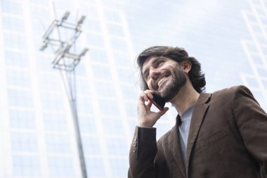 Gündüz vakti akıllı telefonlu genç bir adamın arka planda şehir manzaralı görüntüsü. Yüksek kalite fotoğraf.