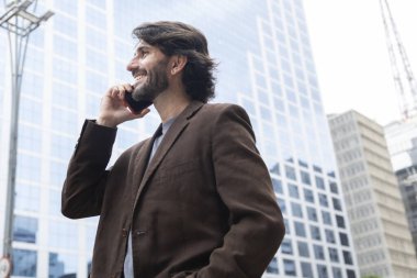 Gündüz vakti akıllı telefonlu genç bir adamın arka planda şehir manzaralı görüntüsü. Yüksek kalite fotoğraf.