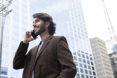 Gündüz vakti akıllı telefonlu genç bir adamın arka planda şehir manzaralı görüntüsü. Yüksek kalite fotoğraf.