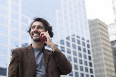 Gündüz vakti akıllı telefonlu genç bir adamın arka planda şehir manzaralı görüntüsü. Yüksek kalite fotoğraf.