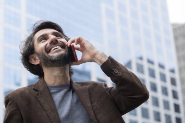 Gündüz vakti akıllı telefonlu genç bir adamın arka planda şehir manzaralı görüntüsü. Yüksek kalite fotoğraf.