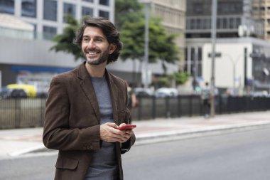 Gündüz vakti akıllı telefonlu genç bir adamın arka planda şehir manzaralı görüntüsü. Yüksek kalite fotoğraf.