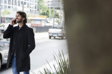 Gündüz vakti akıllı telefonlu genç bir adamın arka planda şehir manzaralı görüntüsü. Yüksek kalite fotoğraf.