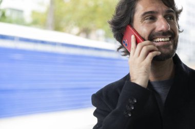 Gündüz vakti akıllı telefonlu genç bir adamın arka planda şehir manzaralı görüntüsü. Yüksek kalite fotoğraf.