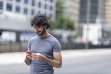 Gündüz vakti akıllı telefonlu genç bir adamın arka planda şehir manzaralı görüntüsü. Yüksek kalite fotoğraf.