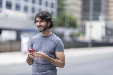 Gündüz vakti akıllı telefonlu genç bir adamın arka planda şehir manzaralı görüntüsü. Yüksek kalite fotoğraf.
