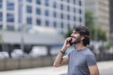 Gündüz vakti akıllı telefonlu genç bir adamın arka planda şehir manzaralı görüntüsü. Yüksek kalite fotoğraf.
