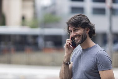Gündüz vakti akıllı telefonlu genç bir adamın arka planda şehir manzaralı görüntüsü. Yüksek kalite fotoğraf.