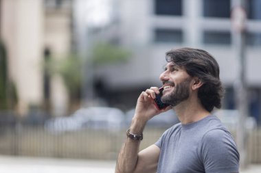 Gündüz vakti akıllı telefonlu genç bir adamın arka planda şehir manzaralı görüntüsü. Yüksek kalite fotoğraf.