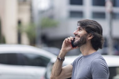 Gündüz vakti akıllı telefonlu genç bir adamın arka planda şehir manzaralı görüntüsü. Yüksek kalite fotoğraf.