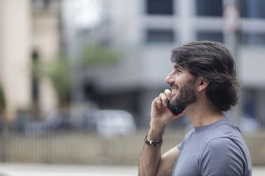 Gündüz vakti akıllı telefonlu genç bir adamın arka planda şehir manzaralı görüntüsü. Yüksek kalite fotoğraf.
