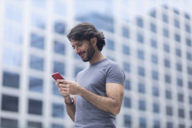 Gündüz vakti akıllı telefonlu genç bir adamın arka planda şehir manzaralı görüntüsü. Yüksek kalite fotoğraf.