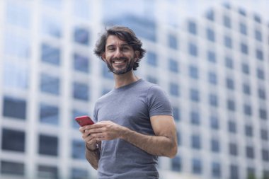 Gündüz vakti akıllı telefonlu genç bir adamın arka planda şehir manzaralı görüntüsü. Yüksek kalite fotoğraf.