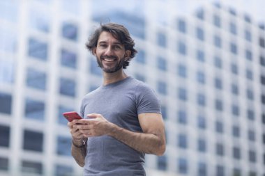 Gündüz vakti akıllı telefonlu genç bir adamın arka planda şehir manzaralı görüntüsü. Yüksek kalite fotoğraf.