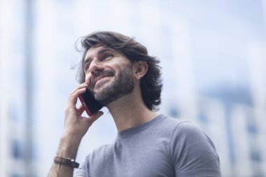 Gündüz vakti akıllı telefonlu genç bir adamın arka planda şehir manzaralı görüntüsü. Yüksek kalite fotoğraf.