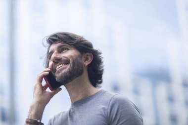 Gündüz vakti akıllı telefonlu genç bir adamın arka planda şehir manzaralı görüntüsü. Yüksek kalite fotoğraf.