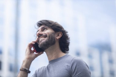 Gündüz vakti akıllı telefonlu genç bir adamın arka planda şehir manzaralı görüntüsü. Yüksek kalite fotoğraf.