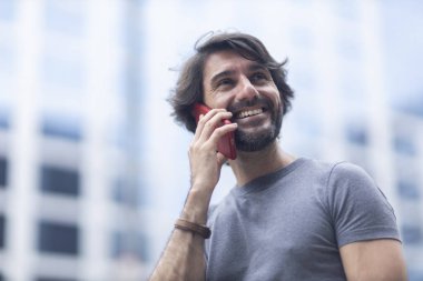 Gündüz vakti akıllı telefonlu genç bir adamın arka planda şehir manzaralı görüntüsü. Yüksek kalite fotoğraf.