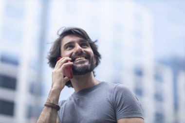 Gündüz vakti akıllı telefonlu genç bir adamın arka planda şehir manzaralı görüntüsü. Yüksek kalite fotoğraf.