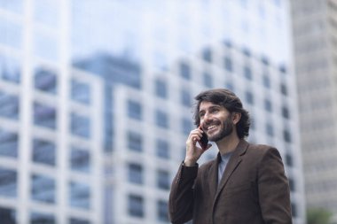 Gündüz vakti akıllı telefonlu genç bir adamın arka planda şehir manzaralı görüntüsü. Yüksek kalite fotoğraf.