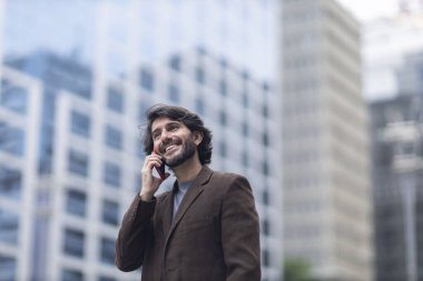 Gündüz vakti akıllı telefonlu genç bir adamın arka planda şehir manzaralı görüntüsü. Yüksek kalite fotoğraf.