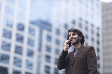 Gündüz vakti akıllı telefonlu genç bir adamın arka planda şehir manzaralı görüntüsü. Yüksek kalite fotoğraf.