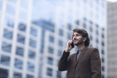 Gündüz vakti akıllı telefonlu genç bir adamın arka planda şehir manzaralı görüntüsü. Yüksek kalite fotoğraf.