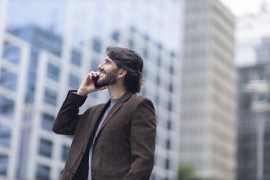 Gündüz vakti akıllı telefonlu genç bir adamın arka planda şehir manzaralı görüntüsü. Yüksek kalite fotoğraf.