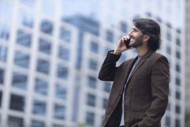 Gündüz vakti akıllı telefonlu genç bir adamın arka planda şehir manzaralı görüntüsü. Yüksek kalite fotoğraf.