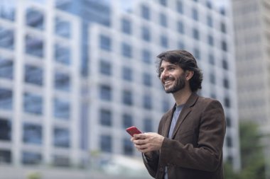 Gündüz vakti akıllı telefonlu genç bir adamın arka planda şehir manzaralı görüntüsü. Yüksek kalite fotoğraf.