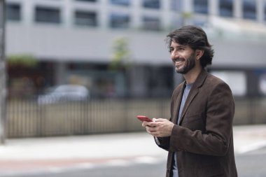 Gündüz vakti akıllı telefonlu genç bir adamın arka planda şehir manzaralı görüntüsü. Yüksek kalite fotoğraf.