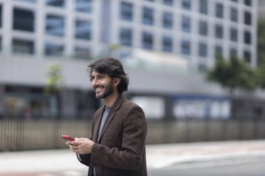 Gündüz vakti akıllı telefonlu genç bir adamın arka planda şehir manzaralı görüntüsü. Yüksek kalite fotoğraf.