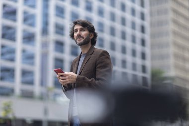 Gündüz vakti akıllı telefonlu genç bir adamın arka planda şehir manzaralı görüntüsü. Yüksek kalite fotoğraf.