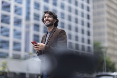 Gündüz vakti akıllı telefonlu genç bir adamın arka planda şehir manzaralı görüntüsü. Yüksek kalite fotoğraf.