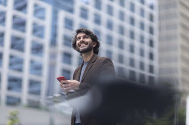 Gündüz vakti akıllı telefonlu genç bir adamın arka planda şehir manzaralı görüntüsü. Yüksek kalite fotoğraf.