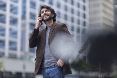 Gündüz vakti akıllı telefonlu genç bir adamın arka planda şehir manzaralı görüntüsü. Yüksek kalite fotoğraf.