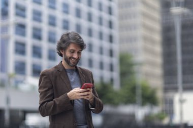 Gündüz vakti akıllı telefonlu genç bir adamın arka planda şehir manzaralı görüntüsü. Yüksek kalite fotoğraf.
