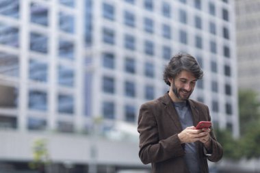 Gündüz vakti akıllı telefonlu genç bir adamın arka planda şehir manzaralı görüntüsü. Yüksek kalite fotoğraf.