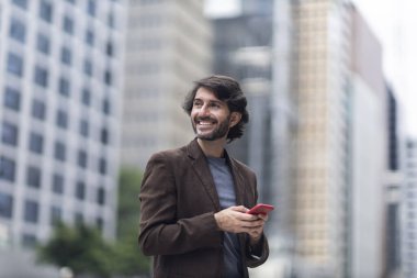 Gündüz vakti akıllı telefonlu genç bir adamın arka planda şehir manzaralı görüntüsü. Yüksek kalite fotoğraf.