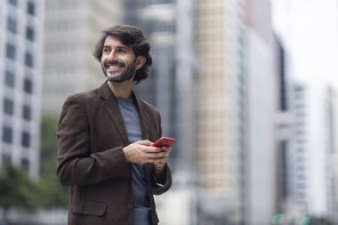 Gündüz vakti akıllı telefonlu genç bir adamın arka planda şehir manzaralı görüntüsü. Yüksek kalite fotoğraf.