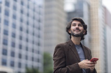 Gündüz vakti akıllı telefonlu genç bir adamın arka planda şehir manzaralı görüntüsü. Yüksek kalite fotoğraf.