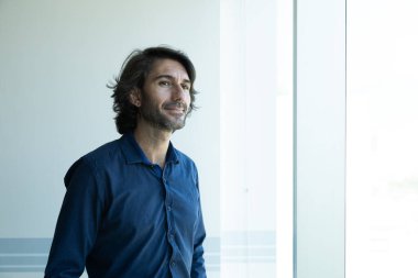 Ofiste arka planda şehir manzarası olan Latin Amerikalı beyaz bir adamın portresi..  