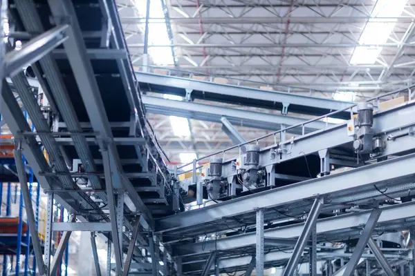 Modern taşıma bantlarının görüntüsü büyük bir depoda kutuları taşımaya hazır.