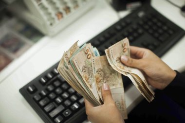 Değişim bürosu / bankada çalışan iş adamının insan eli. O para sayıyor ve bir müşteriye nakit para veriyor. Brezilyalı 50 reais fatura.