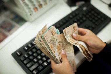 Değişim bürosu / bankada çalışan iş adamının insan eli. O para sayıyor ve bir müşteriye nakit para veriyor. Brezilyalı 50 reais fatura.