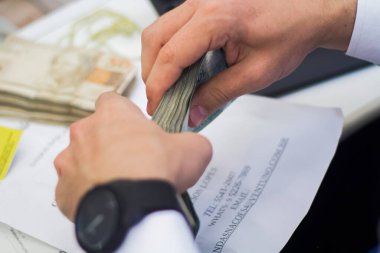 Değişim bürosu / bankada çalışan iş adamının insan eli. O para sayıyor ve bir müşteriye nakit para veriyor. Brezilyalı Reais.