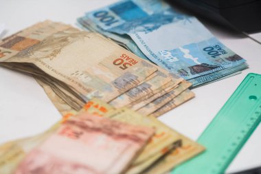 Değişim bürosu / bankada çalışan iş adamının insan eli. O para sayıyor ve bir müşteriye nakit para veriyor. Brezilyalı Reais.