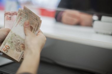 Değişim bürosu / bankada çalışan iş adamının insan eli. O para sayıyor ve bir müşteriye nakit para veriyor. Brezilyalı 50 reais fatura.